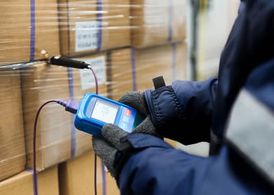 Frozen goods warehouse, worker checking temperature between boxes